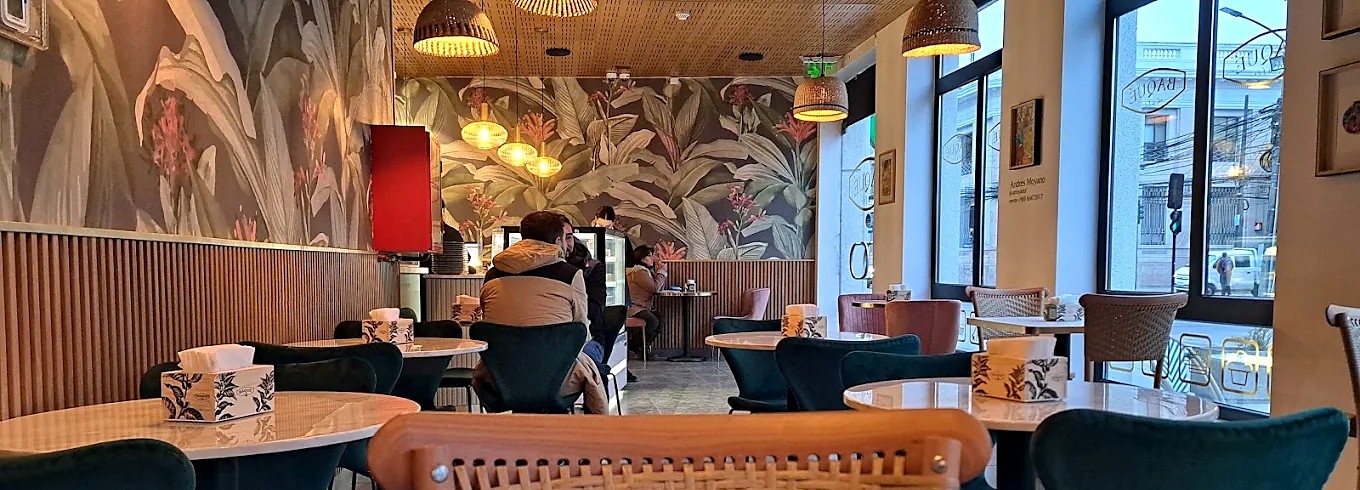 Interior de Café Baqué del Teatro, con murales botánicos y luces colgantes